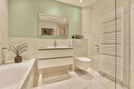 Bathroom Paint Colors for 2026 featuring soft sage green walls, white fixtures, and a clean minimalist bathroom