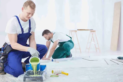 Cabinet Painting Prices: What You’re Really Paying For Two Professional painters preparing and applying coatings, illustrating labor factors that influence cabinet painting prices.