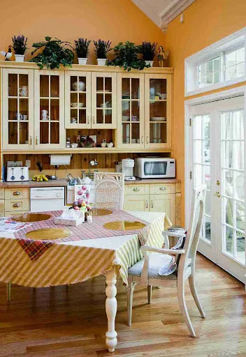 Bright yellow kitchen with painted glass cabinets shows why many homeowners ask if cabinet painting is worth it.