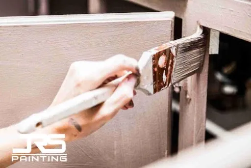 Oil vs Water-Based Cabinet Paint: Which Is Better for Kitchen Cabinets? Close-up of brush applying finish to cabinet frame for Oil vs Water-Based Cabinet Paint comparison.