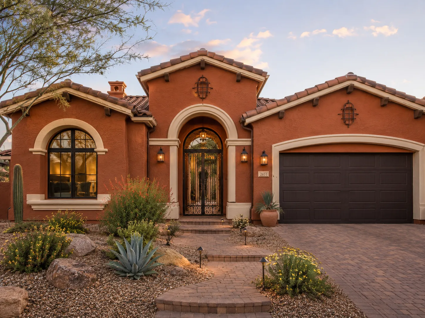 burnt-orange-exterior-paint-ideas-rust-stucco-cream-trim Burnt orange exterior paint ideas on a rust stucco home with cream trim, wrought iron entry, and desert landscaping.