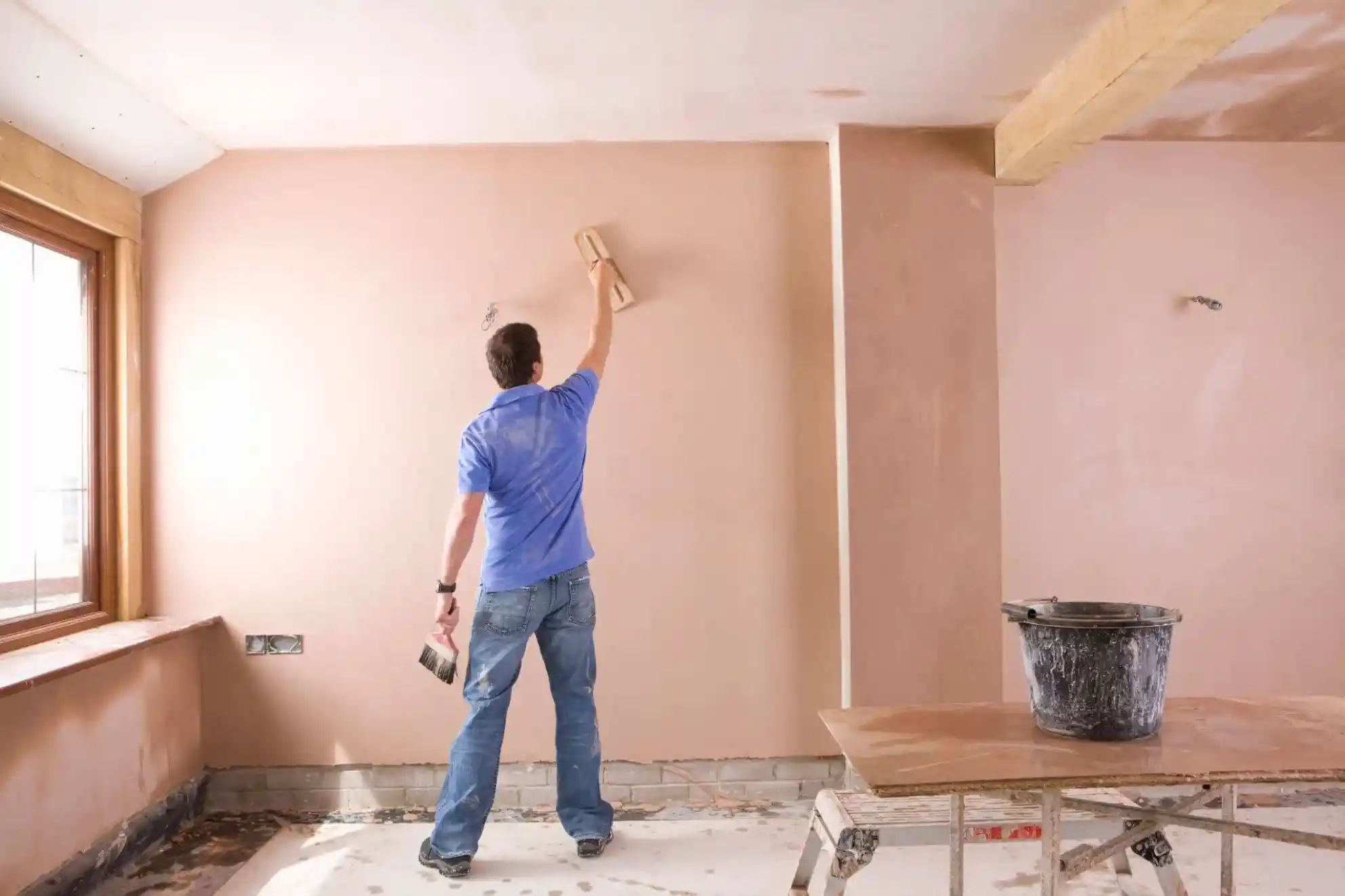 drywall-or-stucco-interior-plaster-wall-finishing Drywall or stucco interior wall being finished by a worker using a plastering trowel